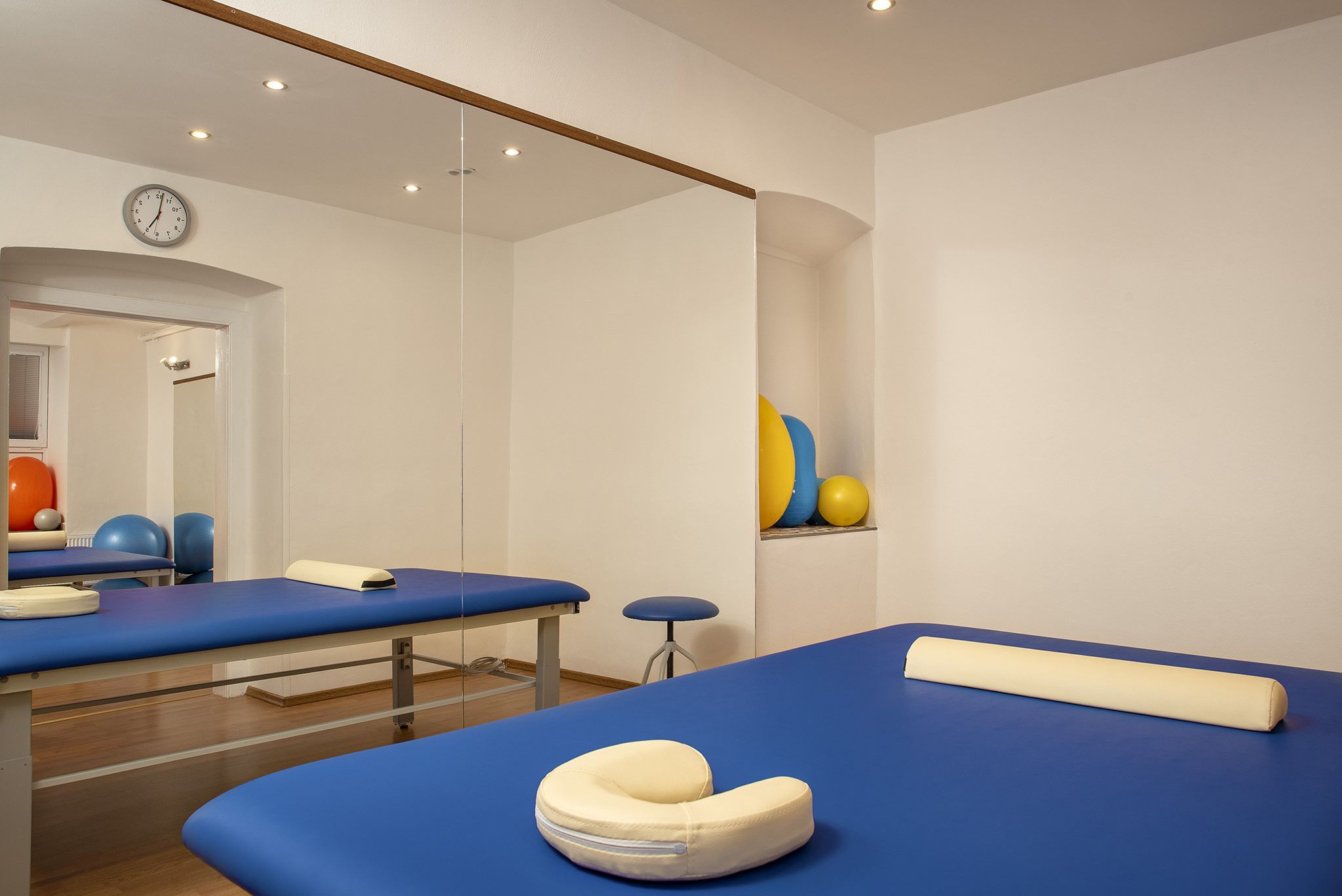 Fyzioterapeutická miestnosť s modrým lôžkom, zrkadlovou stenou a cvičebnými pomôckami